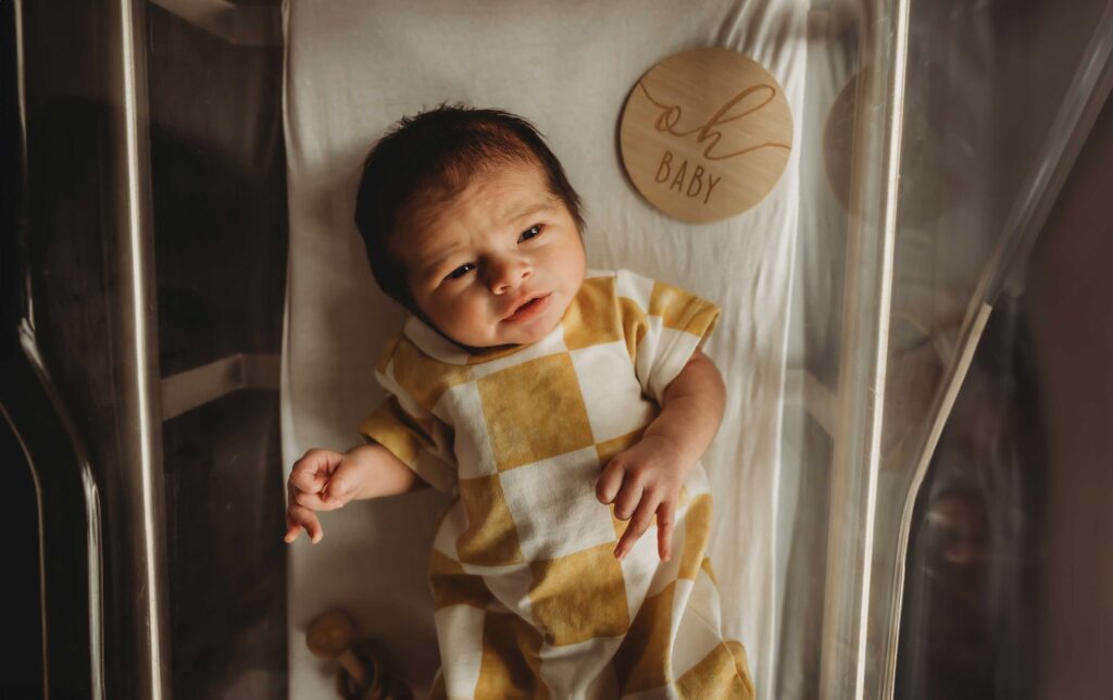newborn baby boy wearing a yellow and white checkered outfit