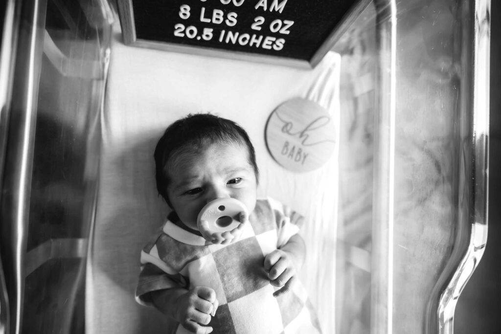 black and white photo of a newborn baby in a hospital crib