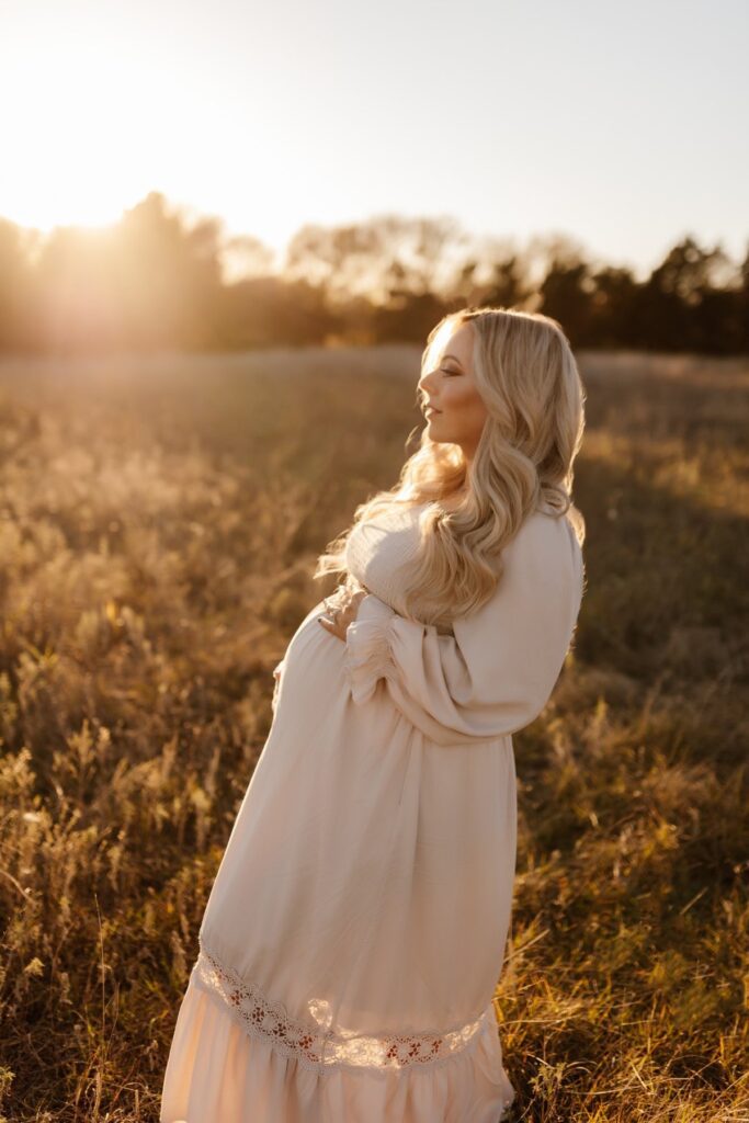 Hands cradling a pregnant belly during a golden hour photo
